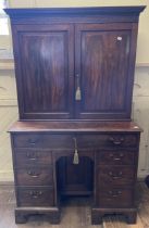 A 19th century mahogany kneehole desk, with a bookcase top having a pair of panel doors, opening