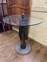 A novelty glass and metal table, in the form of a bomb fin tail, 74 cm diameter