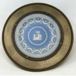 A Wedgwood style Jasperware plate, inset into a brass mount with engraved decoration, 33 cm diameter