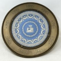 A Wedgwood style Jasperware plate, inset into a brass mount with engraved decoration, 33 cm diameter
