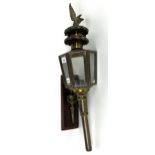 A brass and glass coaching type lamp, mounted on a panel