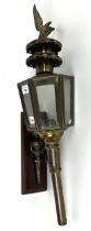 A brass and glass coaching type lamp, mounted on a panel