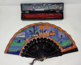 A lacquered fan, decorated figures, paper painted interior scene, 11 cm, boxed, and two other