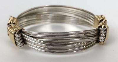 A silver coloured metal and yellow coloured metal adjustable bangle