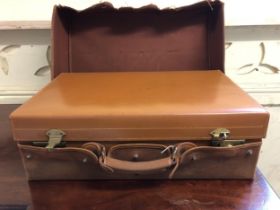 A vintage leather suitcase, inset with various silver topped bottles and silver backed brushes,