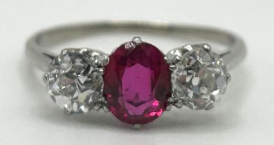 A white coloured metal, synthetic ruby and diamond three stone ring, ring size P A small chip to the