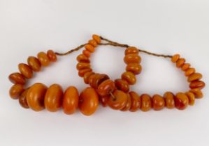 A very large amber coloured bead necklace, the largest bead 7 cm wide, and another similar, the
