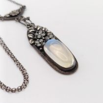 An Arts and Crafts silver coloured metal and moonstone pendant, on a chain, by Jean Bassett