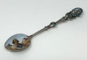 A silver coloured metal and enamel spoon, decorated ancient Egyptian symbols, the finial
