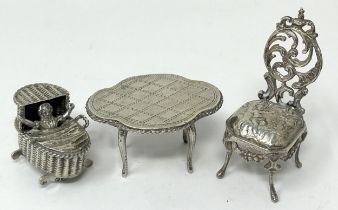 A novelty silver ornament, of a baby in a bassinette, a miniature table and chairs (3)