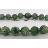 A Chinese carved green stone necklace length: 40 cm approx diameter of bead: 15 mm average approx