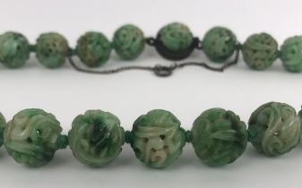 A Chinese carved green stone necklace length: 40 cm approx diameter of bead: 15 mm average approx