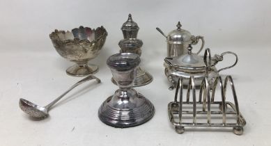 A silver sugar bowl, sifting spoon, a toast rack, two mustard pots, and a pepper, various dates