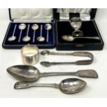 A fiddle pattern spoon, another, a napkin ring, a pair of sugar tongs, an egg cup and spoon,