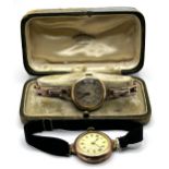 A ladies yellow coloured metal wristwatch, on a silk strap, with a worn vintage watch box, and a