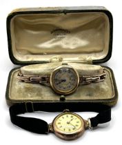 A ladies yellow coloured metal wristwatch, on a silk strap, with a worn vintage watch box, and a