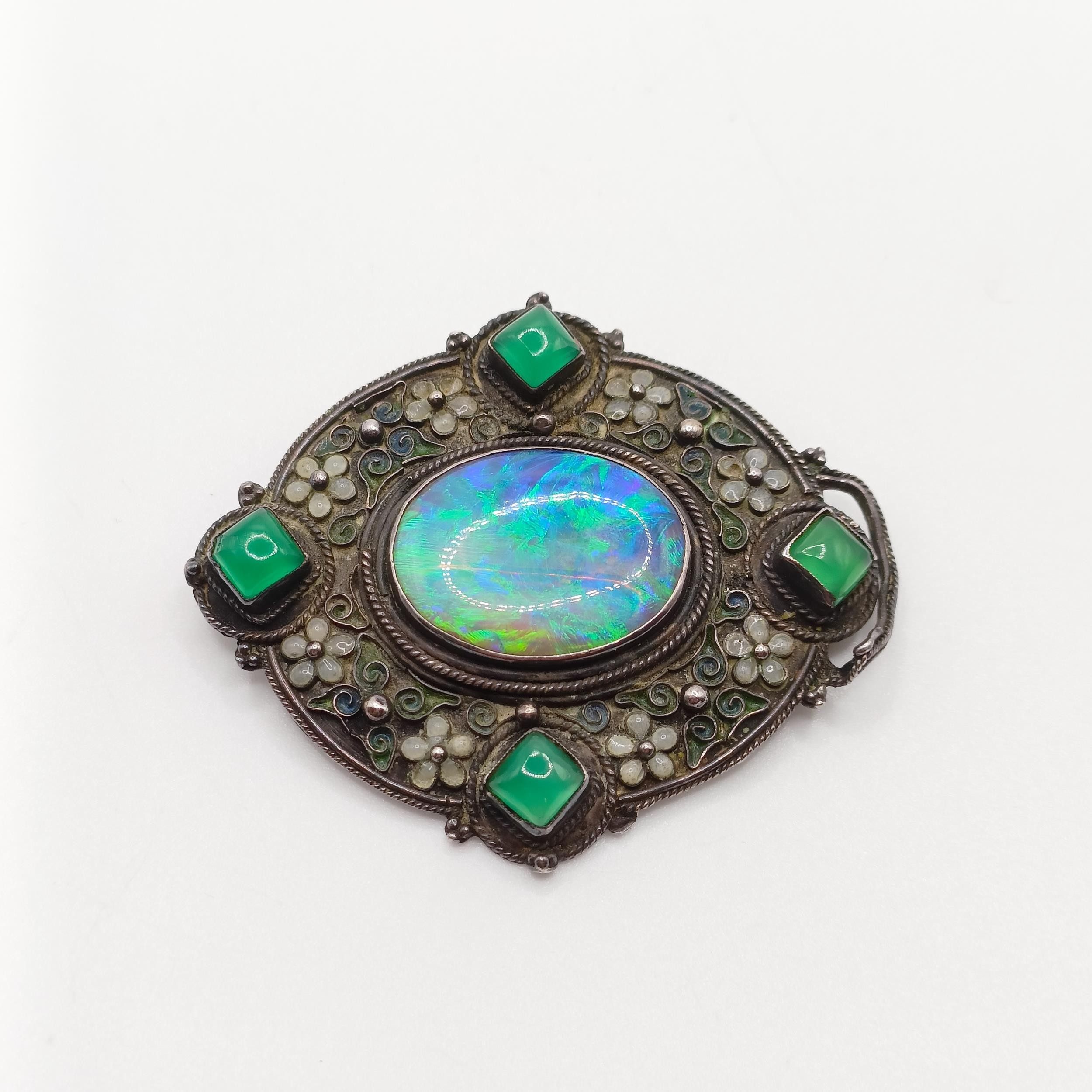 An Arts and Crafts silver coloured metal, opal, green stone and enamel brooch, by Jean Bassett