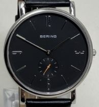 A gentleman's stainless steel Bering wristwatch 13709-402, on a leather strap, in a glass case, with