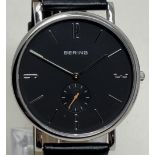 A gentleman's stainless steel Bering wristwatch 13709-402, on a leather strap, in a glass case, with