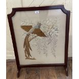 A silk embroidered panel, decorated an exotic bird and blossom, inset in a firescreen with a