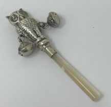 A novelty silver coloured metal and mother of pearl baby's rattle, in the form of an owl
