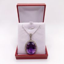 A large oval pendant, in white metal, set with a large faceted oval amethyst and double RBC