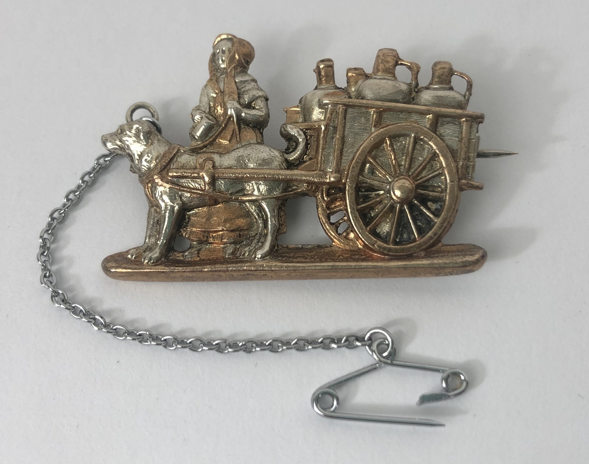 A silver coloured metal brooch, in the form of a lady with a dog cart