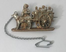 A silver coloured metal brooch, in the form of a lady with a dog cart