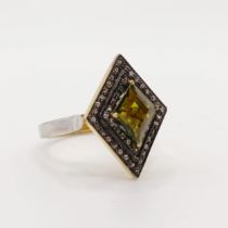 A silver gilt diamond-shaped ring, set with a kite-shaped green tourmaline and double halo of rose-