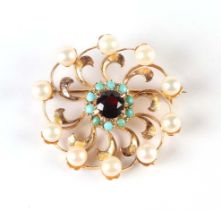 A yellow metal (tests at 18ct gold) flower head brooch set with central garnet within a ring of