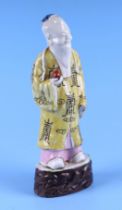 An 18th century Chinese figure depicting Shoulau holding a peach, in polychrome colours, 22cms high.