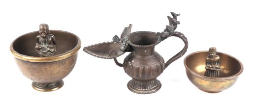 Two Indian brass drunkard cups with central figures, the largest 12cms diameter; together with an