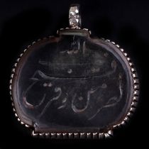 An Islamic white metal mounted rock crystal pendant decorated with Arabic script, 4cms wide.