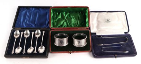 A cased pair of silver napkin rings; together with a boxed set of silver teaspoons and a boxed set