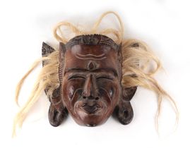 A carved wooden tribal mask, 30cms high.