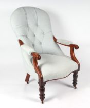A Victorian mahogany button back armchair on turned front supports.