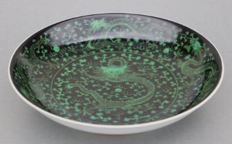 A Chinese famille noir shallow footed bowl decorated with scrolling dragons chasing a flaming pearl,