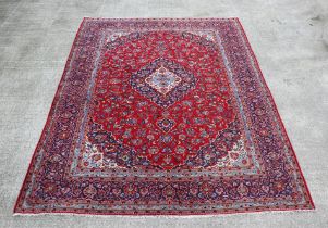 A large Persian Meshed hand knotted wool carpet, the central medallion within a red and floral