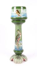 A continental tube lined Art Nouveau jardiniere on stand decorated with birds on a green ground,