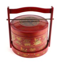 A Chinese red lacquered food carrier with gilt decoration, 26cms diameter.