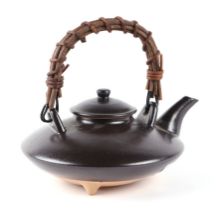 A Japanese pottery teapot of squat form and reed handle, 15cms diameter.