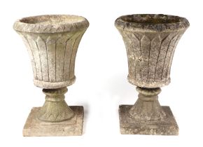 A pair of well weathered reconstituted stone urns on plinths, 44cms diameter (2).