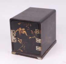 A Japanese lacquer table top cabinet, the single door enclosing three drawers and decorated with