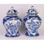 A pair of Chinese blue & white baluster vases and covers decorated with birds seated on foliage
