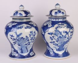 A pair of Chinese blue & white baluster vases and covers decorated with birds seated on foliage