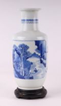 A Chinese blue and white rouleau vase decorated with a river landscape and precious objects, on a