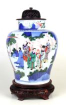 A large Chinese Wucai vase decorated with figures in a landscape, on a pierced hardwood stand and