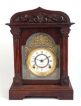 A late 19th century oak cased mantle clock, the white enamel dial with Roman numerals, 27cms wide.