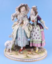 A continental porcelain group depicting two ladies standing by a gate with a spaniel dog, 26cms