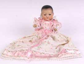 An Armand Marseille bisque headed baby doll with sleeping brown eyes, closed mouth and composite